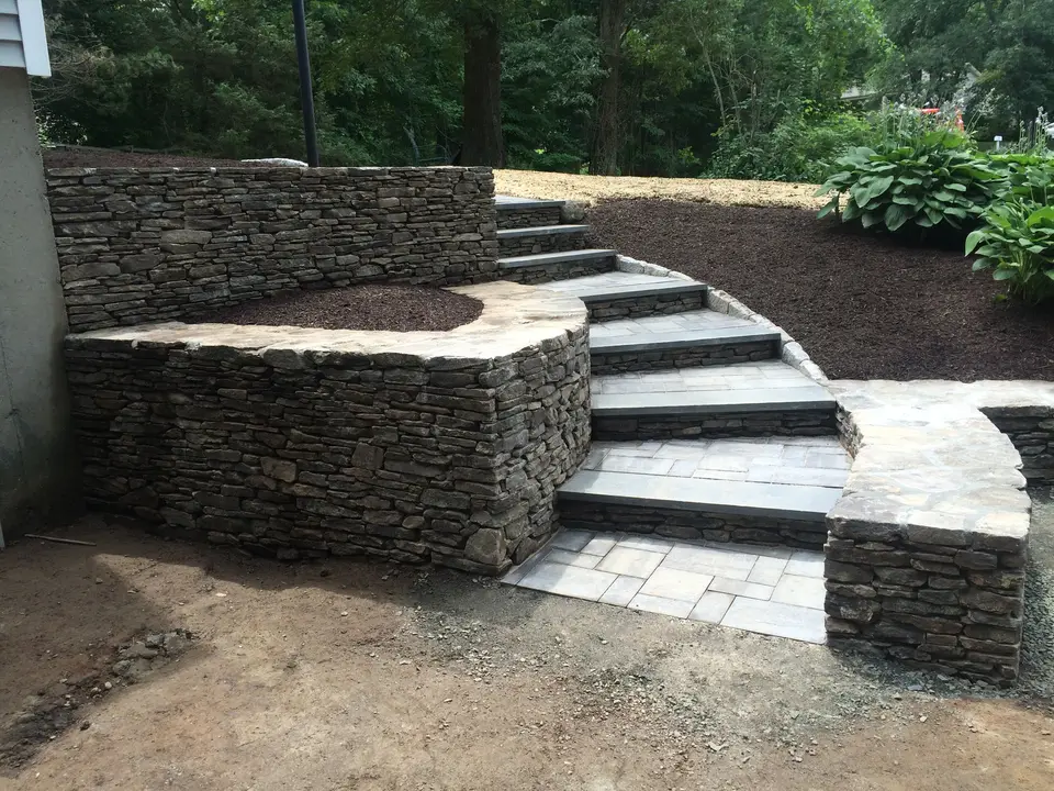 Curved natural stone steps and fieldstone retaining walls built by J&M Landscape Design