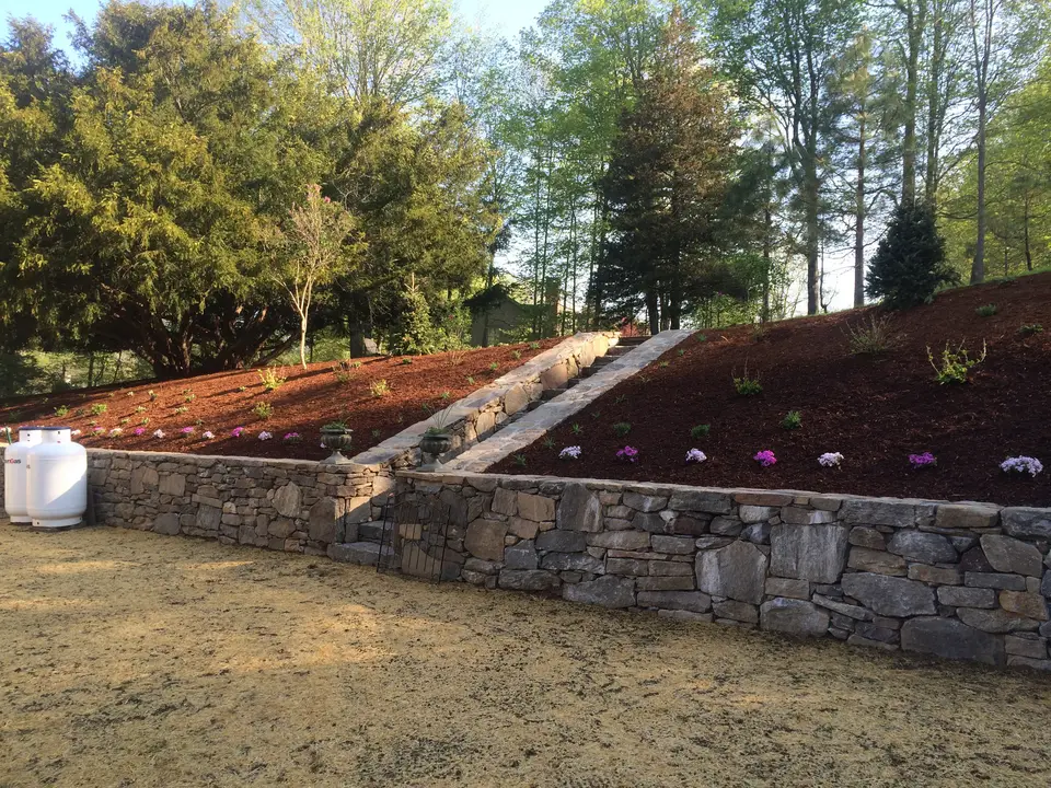 Stone retaining wall with freshly mulched planting beds