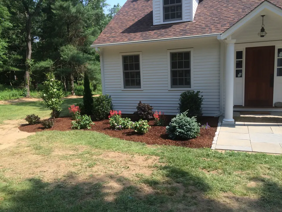 Planted garden beds in front of a white home
